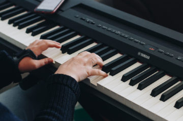 Hände auf Klaviertasten in der Nahansicht. Klavier lernen für Anfänger.