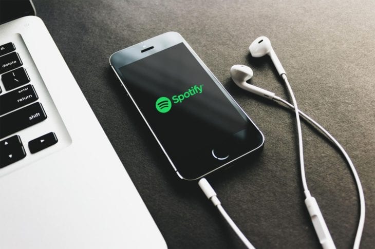Ein Handy mit Spotify App neben einem Apple Macbook