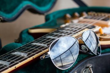 Gitarrenkoffer mit Gitarre und Sonnenbrille symbolisiert Work-Life-Balance für Musiker*innen