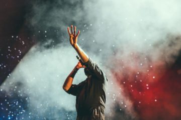 Träume verwirklichen als Musiker*in - ein Musiker greift mit Mikro in der Hand nach den Sternen