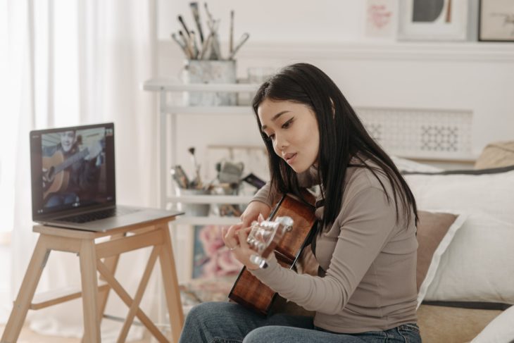  Guitar learning apps - Asian woman with guitar in front of laptop