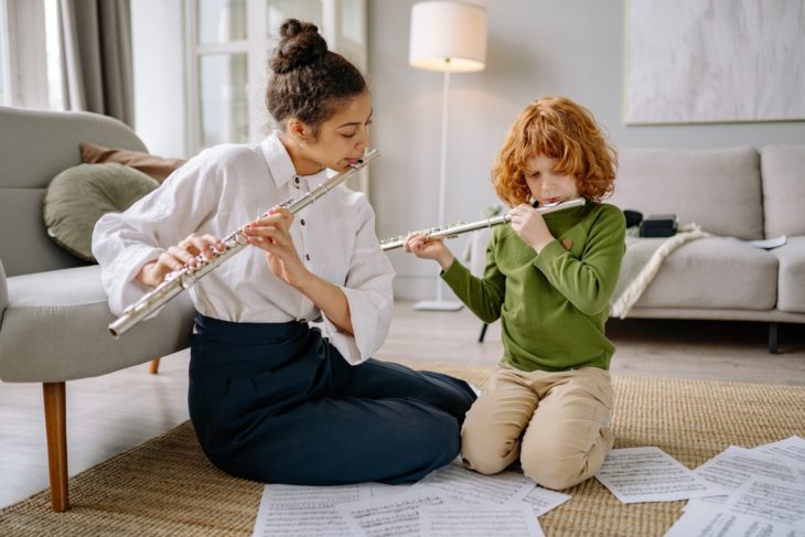 Musikinstrumente für Kinder – Mutter mit Tochter übt Querflöte spielen