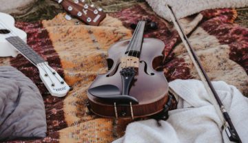 Eine Frau spielt draußen Violine, der Hintergrund ist unscharf, der Fokus liegt auf der Violine