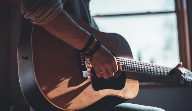 Eine Person spielt Gitarre, die Gitarre wird von der Sonne angeleuchtet