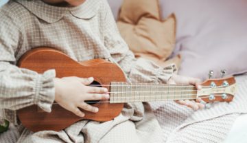Eine Nahaufnahme eines Menschen der oder die ein altes Saiteninstrument spielt