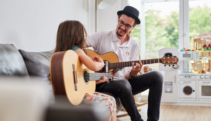 Bild zeigt eine junge Musikerin an der Gitarre beim Gitarrenunterricht zum Thema: Musikunterricht online via Homeschooling